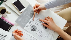Twee collega's bekijken samen een onderzoeksrapport met cirkeldiagrammen en percentages