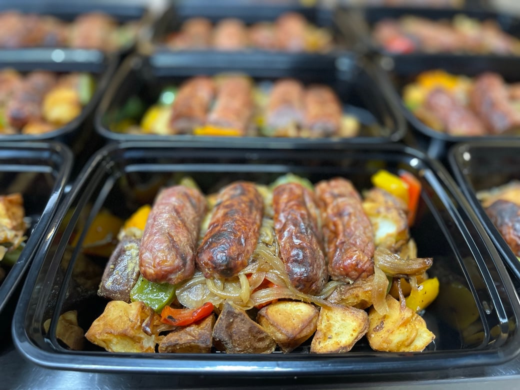 Grilled bratwurst over mustard-roasted potatoes, sautéed peppers and onions