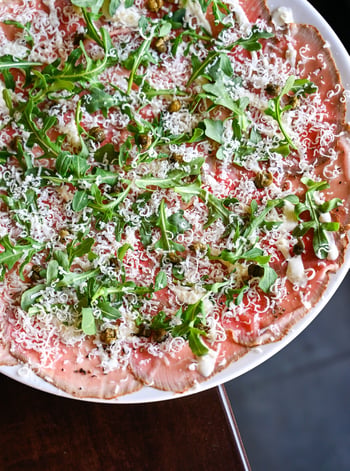 Beef Carpaccio done right is one of the quieter pleasures on a menu. At BellaBrava, it arrives with arugula, lemon oil, Grana Padano, crispy capers, and a lemon caper aioli that pulls everything into focus. The kind of antipasti that makes you slow down and pay attention. Beach Drive has been serving it this way for twenty years.

📸: Beef Carpaccio 

#bellabrava #stpete #carpaccio #antipasti #italianfood