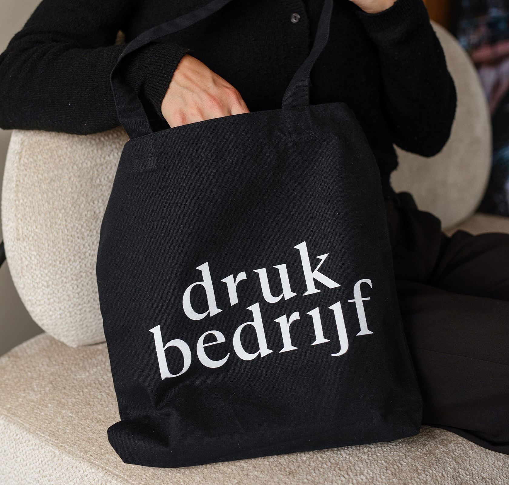 zwarte canvas tas bedrukt met logo die mensen blijven dragen, hand die in de tas gaat