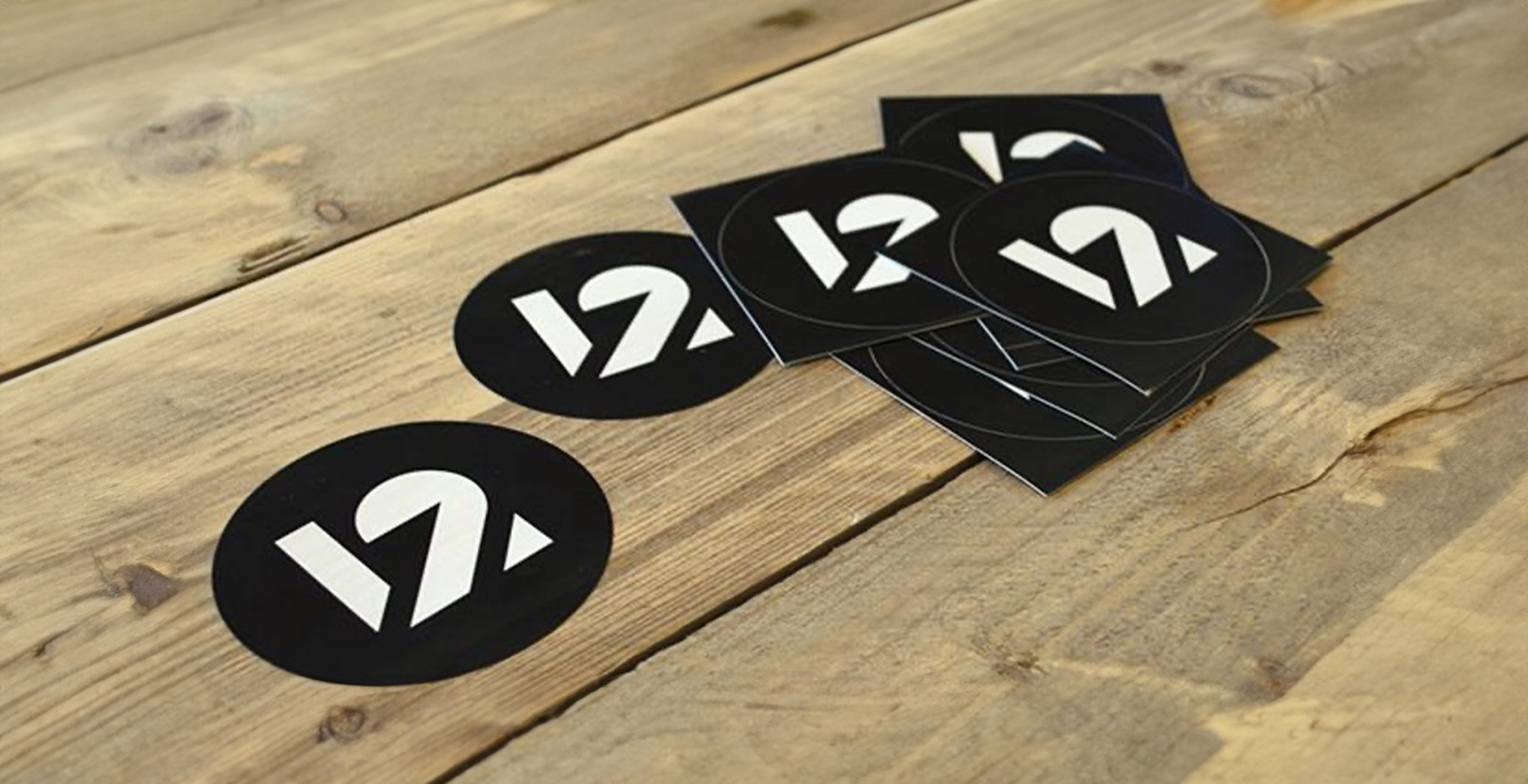 Logo stickers bedrukken voor twelve zwart wit met logo op houten tafel.