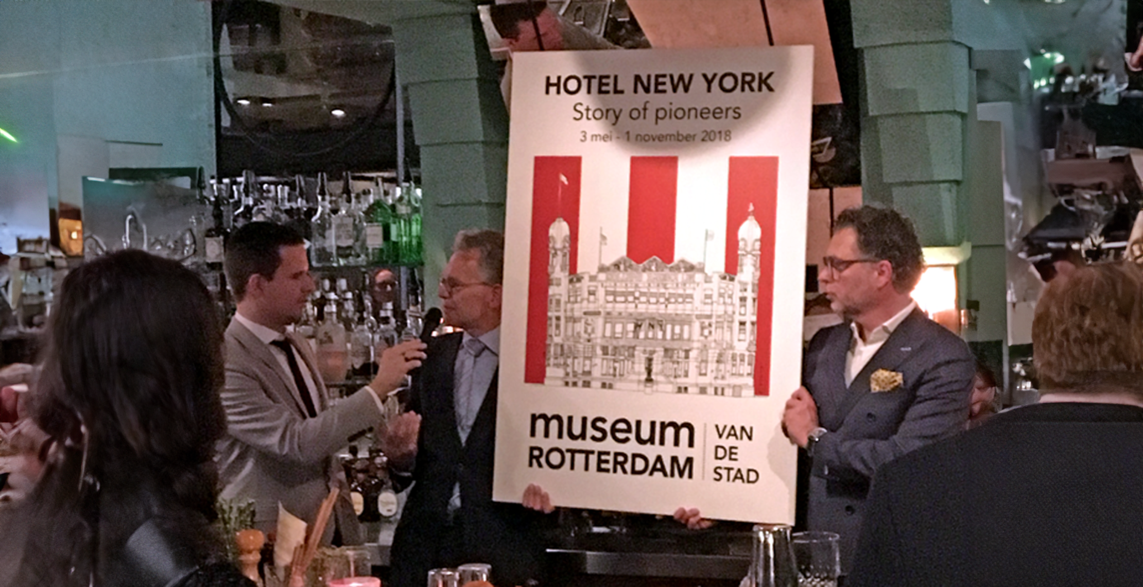 Onthulling nieuwe tentoonstelling Museum Rotterdam met een groot forex bord bedrukt met poster van hotel new york.