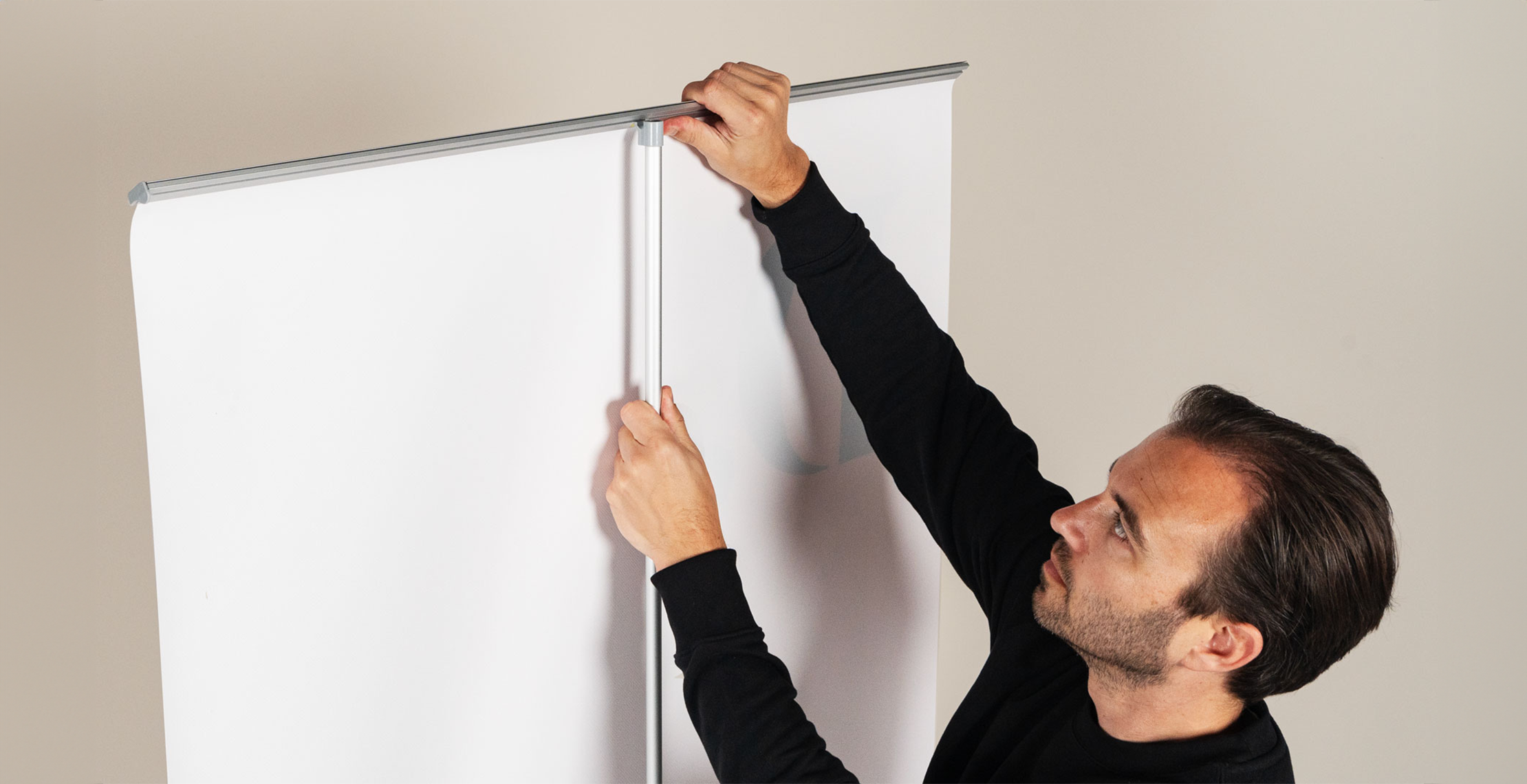 roll-up banner opzetten door man die het roll-up banner doek vastzet op de stang.