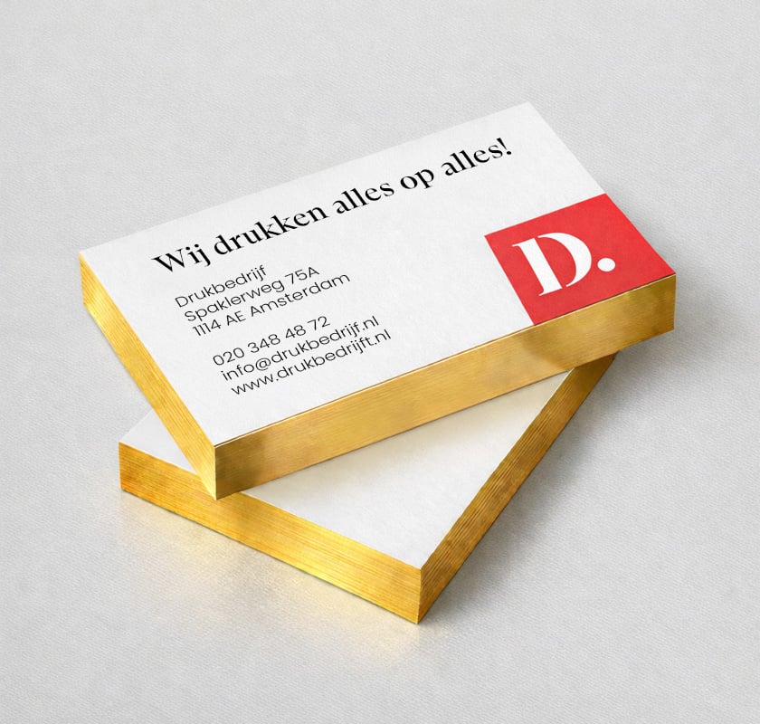Visitekaartje met gouden druk op snede aan de zijkant. Twee stapeltjes waar het goud goed zichtbaar is aan de zijkant van de visitekaartjes. 