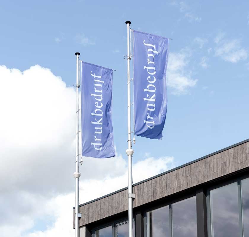 gepersonaliseerde vlaggen wapperend boven drukbedrijf in amsterdam blauwe lucht