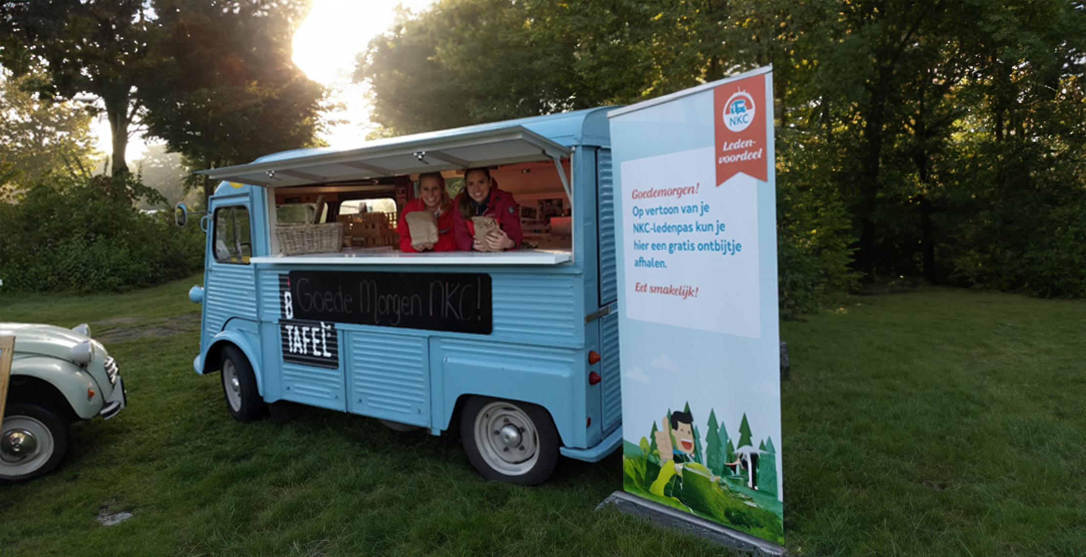 NKC trailer waar twee meiden naar buiten kijken en een roll up banner naast staat. 