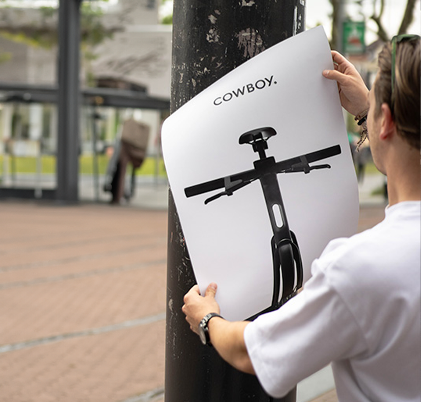 Cowboy poster wordt opgehangen door jongen in Amsterdam.