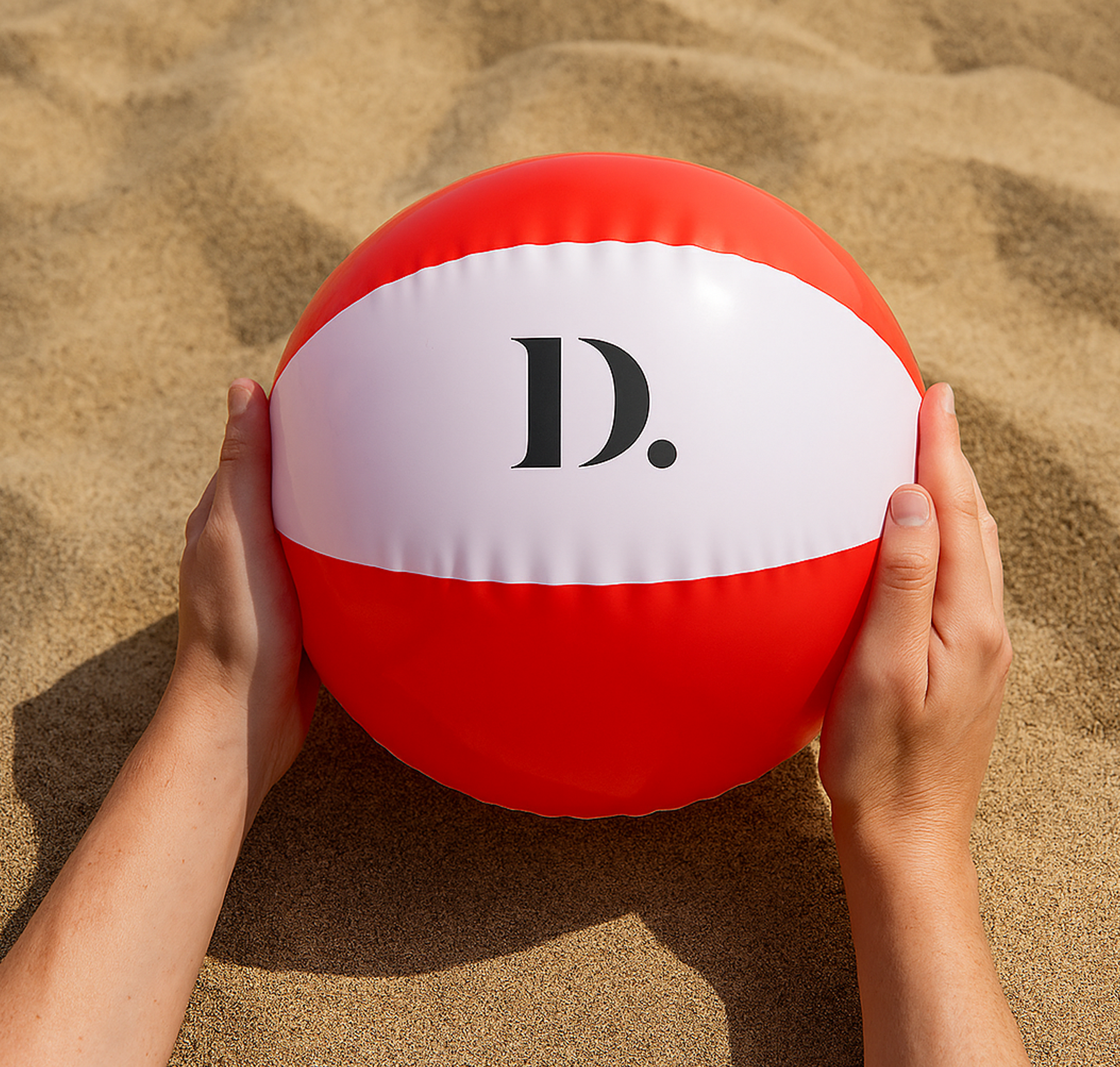 bedrukte strandbal rood wit bedrukt op zand in handen