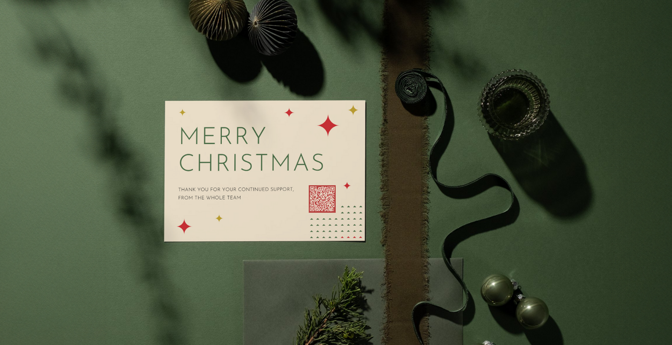 bedrukte kerstkaart met qr code en merry christmas op de kaart liggend op groene achtergrond met linten en kerstballen