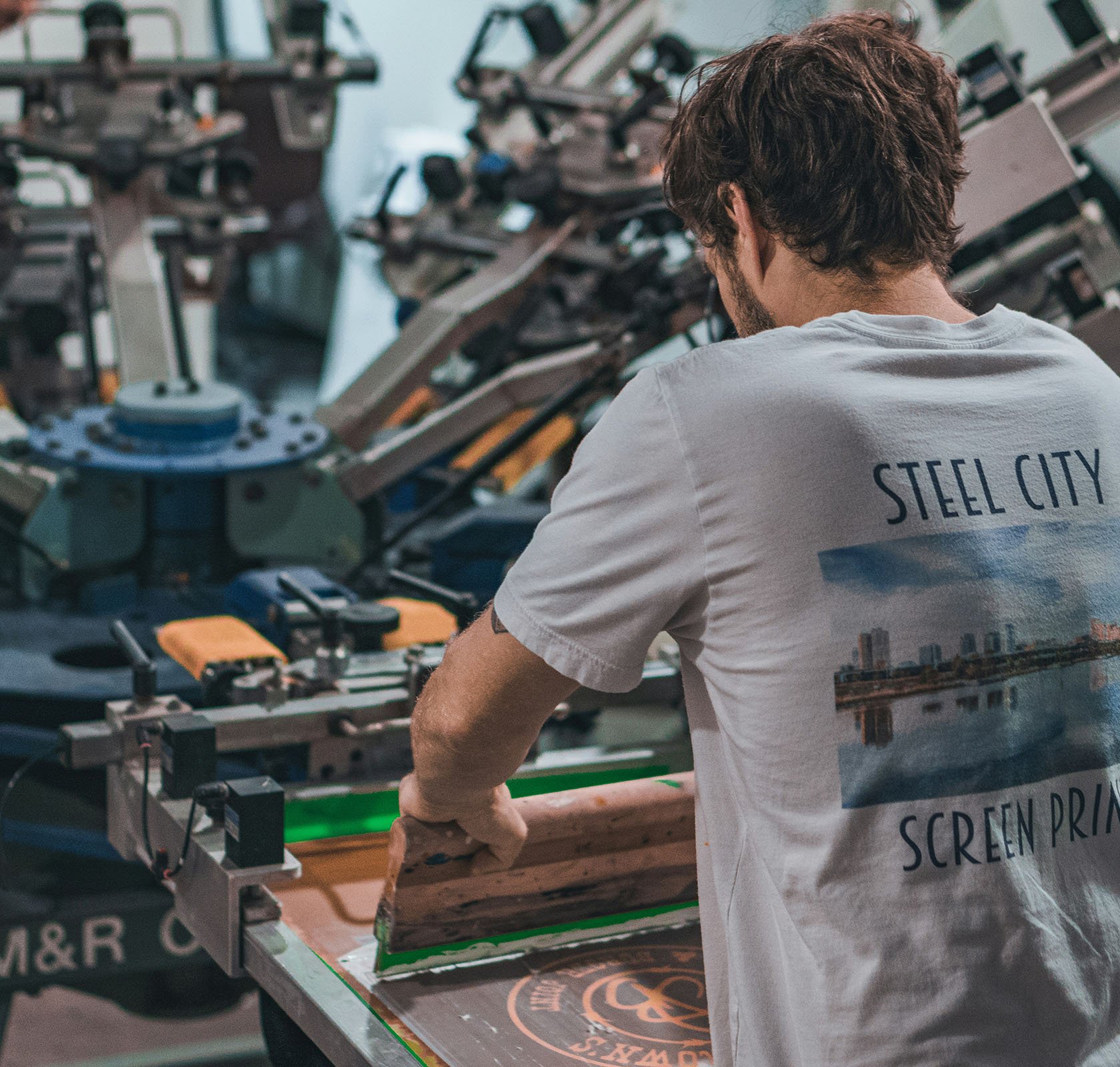 Zeefdrukcarroussel aan de slag met man die ook zeefdrukt op een shirt