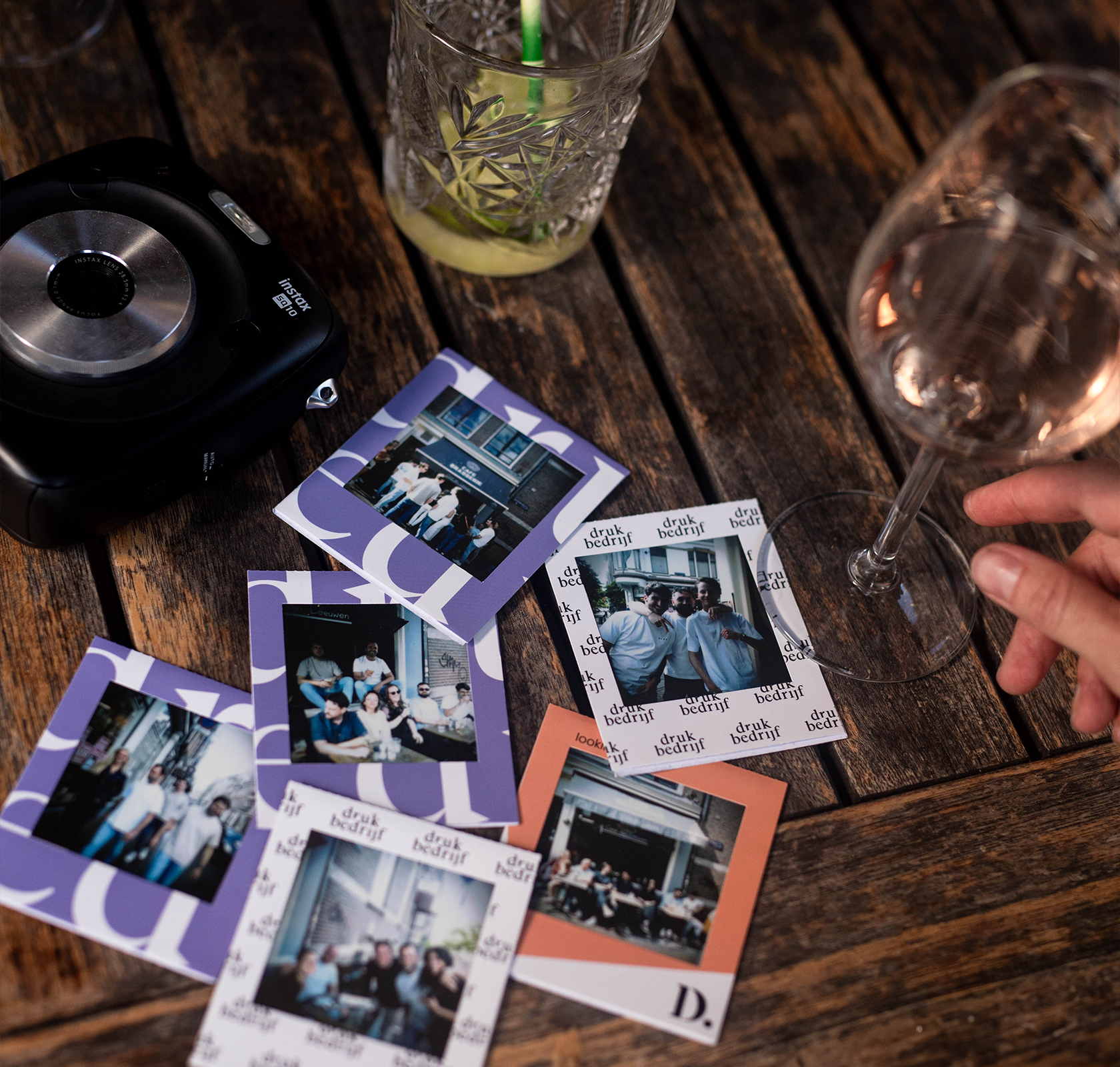 Polaroid frames met logo op tafel naast drankjes tijdens personeelsuitje in Amsterdam.