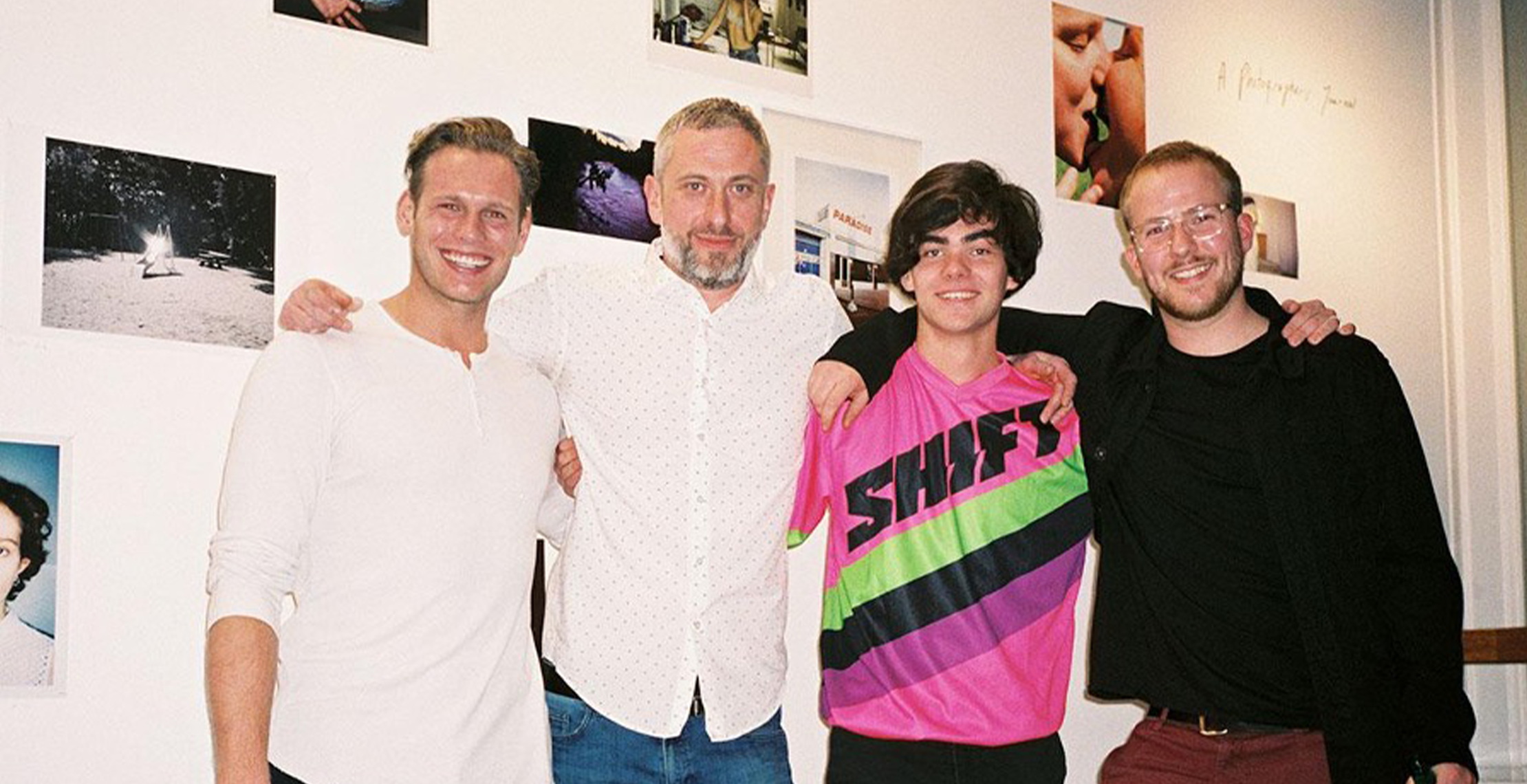 vier mannen arm in arm met muur met foto's achter hun van cloud gallery