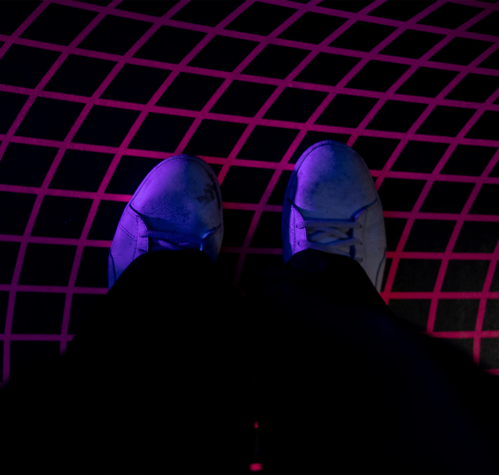 Witte sneakers staan op vloer bedrukt met neon geprinte sticker