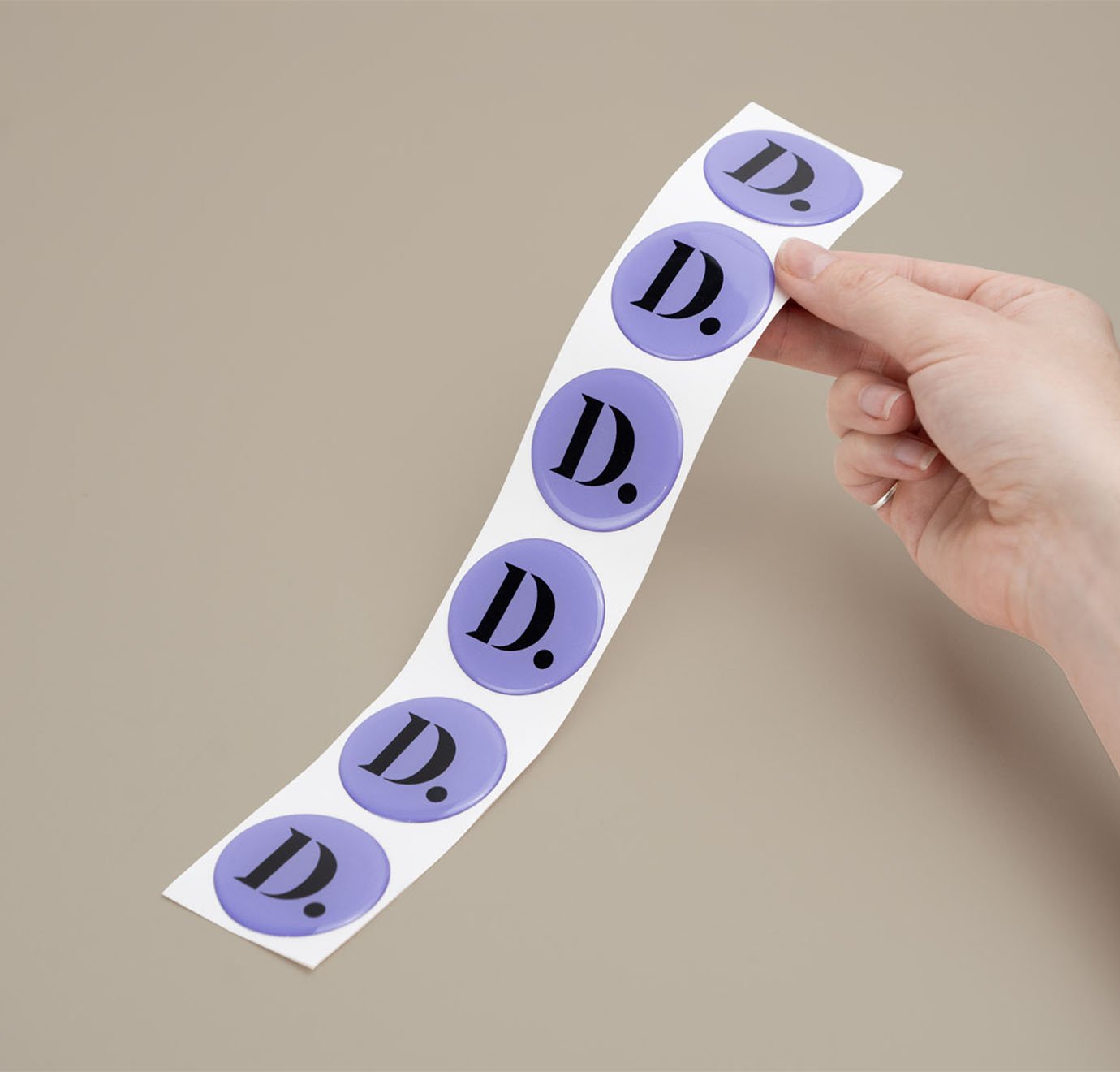 paarse domed stickers bedrukt met logo in hand vastgehouden