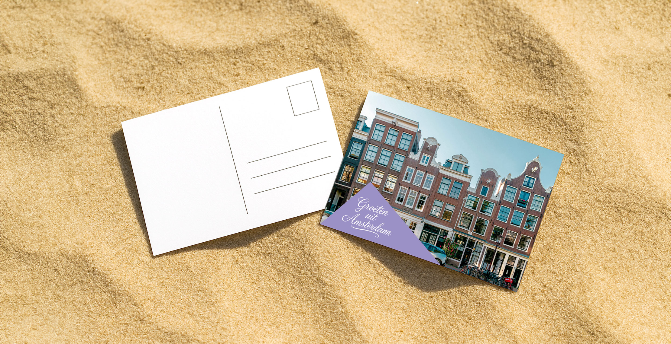 ansichtkaart met groeten uit Amsterdam ligt op het zomerse zand