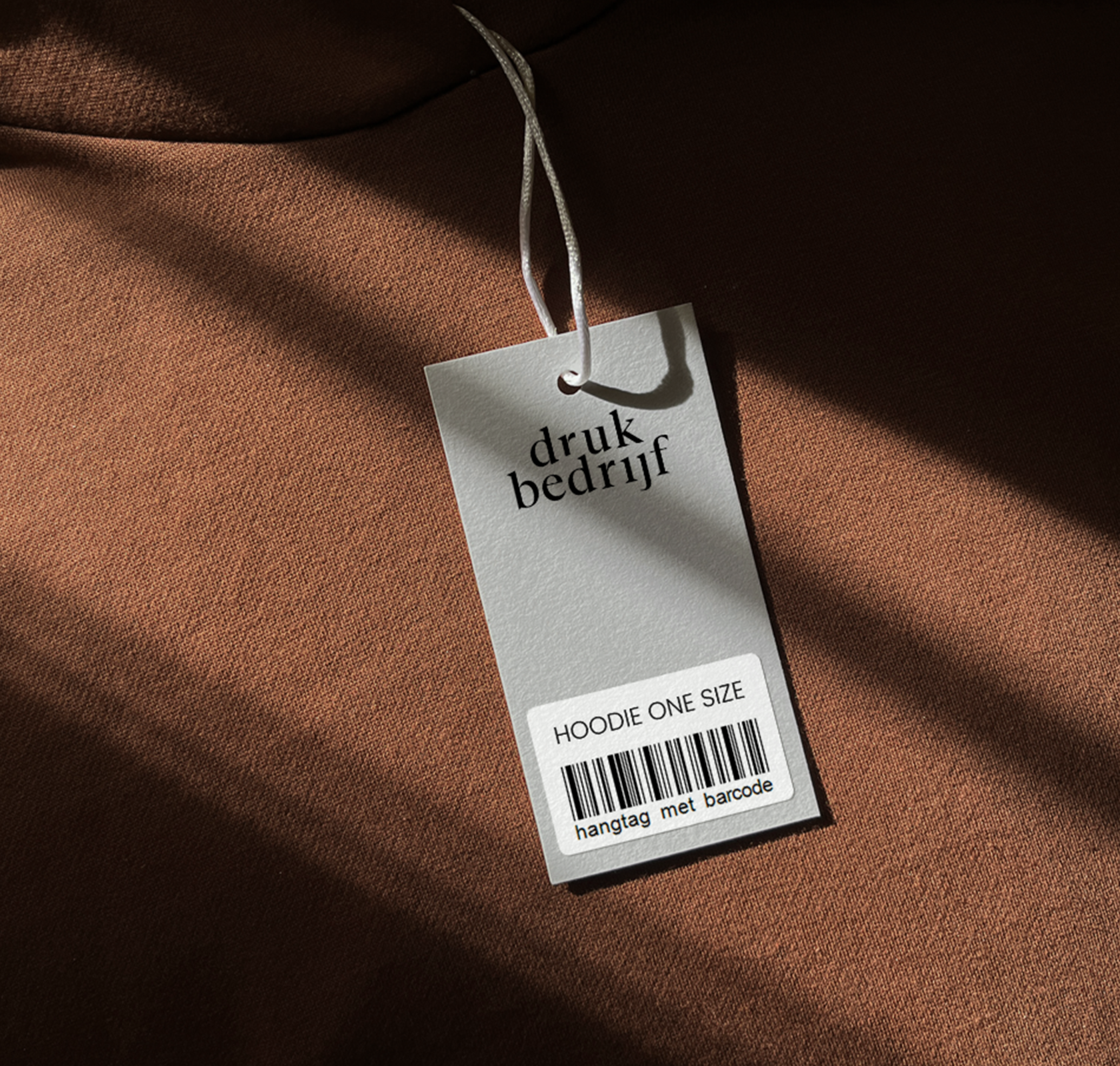 Bedrukte hangtag met barcode op bruine trui met licht inval