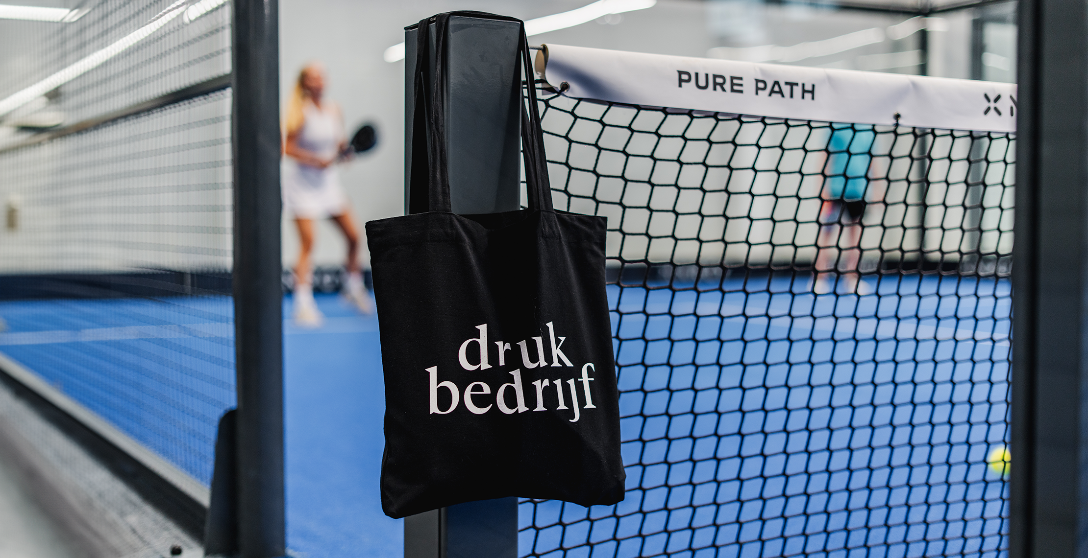 bedrukte canvas tas hangend aan padelnet