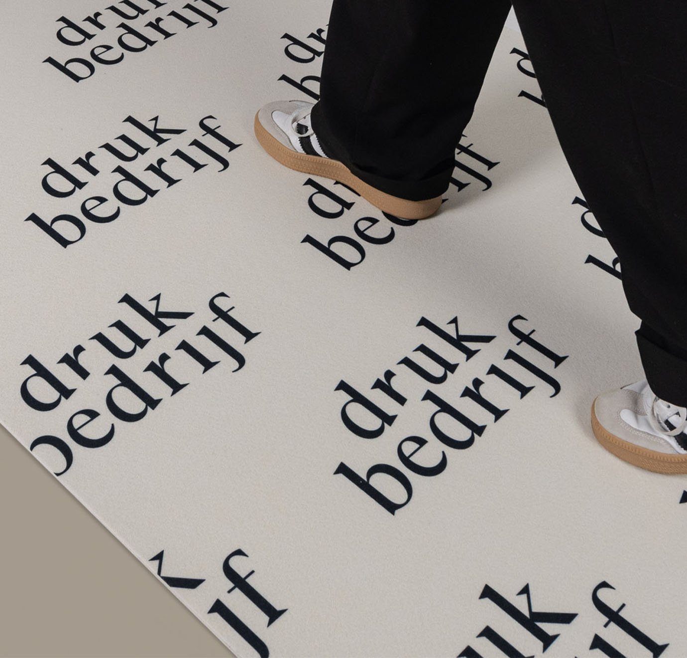 Persoon loopt over wit beurstapijt bedrukt met logo van drukbedrijf.