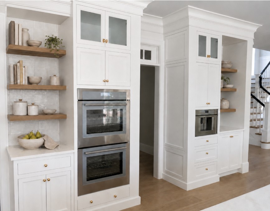 Rendering of a kitchen with white cabinetry, stainless steel wall ovens, brass hardware, wooden open shelving, and wood flooring in Cohasset.