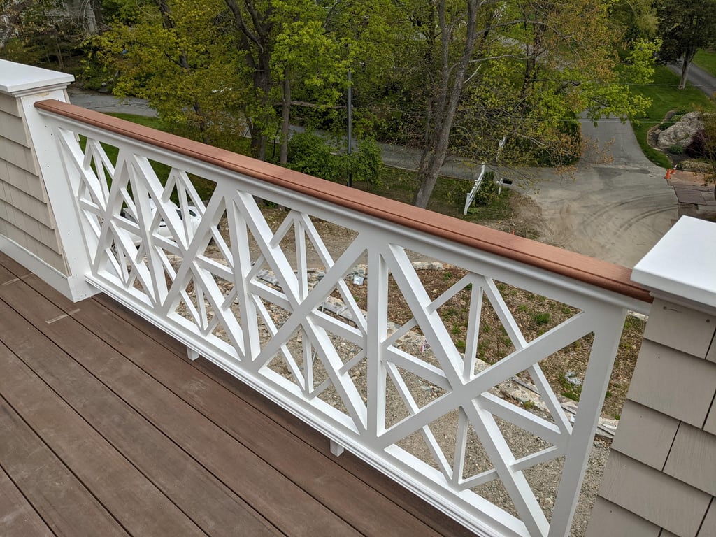 Completed deck with white X-pattern railing and brown top cap overlooking wooded area in Cohasset.