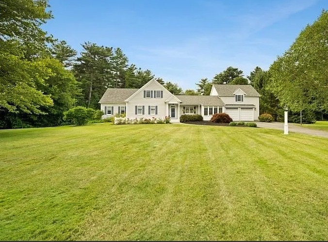 Front exterior of a white two-story house with attached garage in Lakeville, set on a manicured lawn with mature trees.