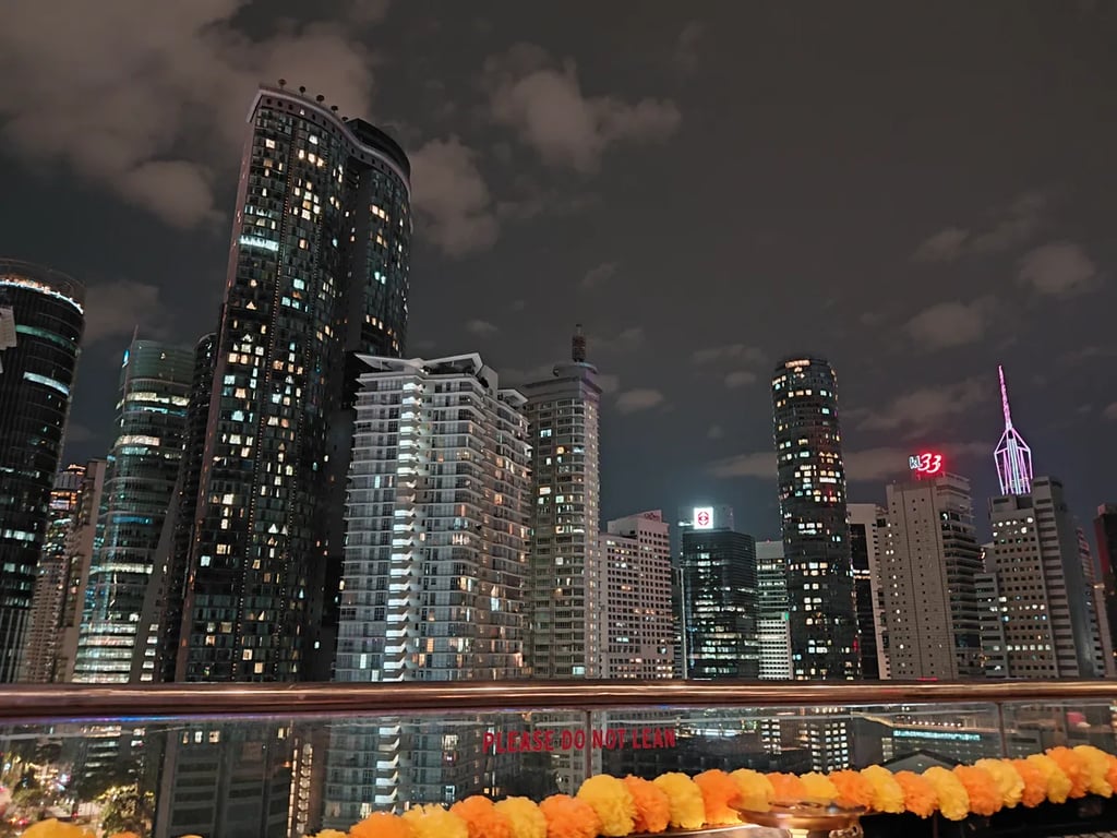Kuala Lumpur towers lit up at night behind a garland of marigolds