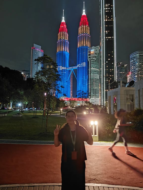 Standing in front of the Petronas Towers lit blue and red at night