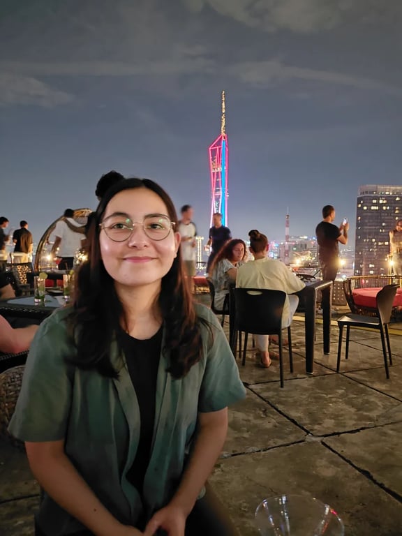 On a rooftop bar terrace with KL Tower lit up behind