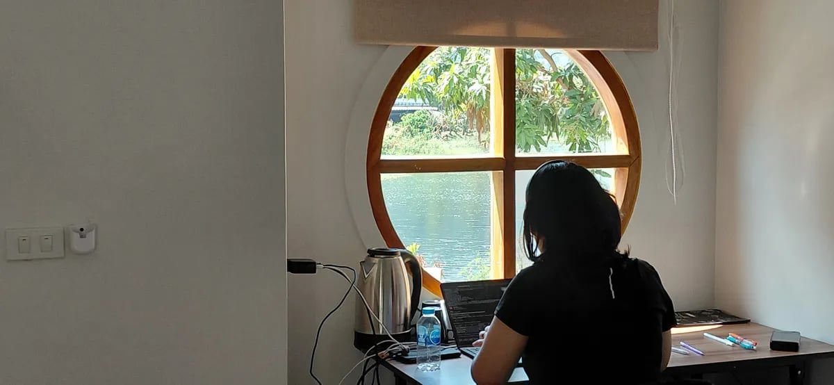 Working at a desk beside a round window looking out over the water in Phuket