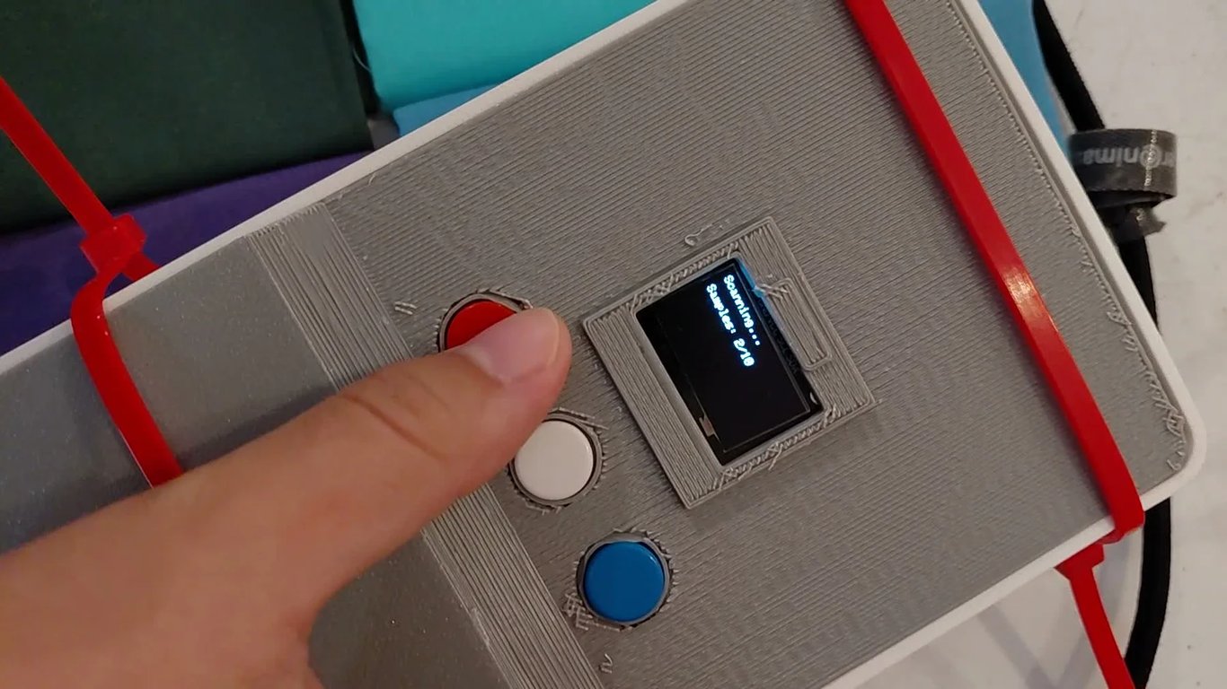 Fabric Colour Sensor scanning a sample at Liverpool MakeFest with its OLED active and enclosure secured with two red zip ties