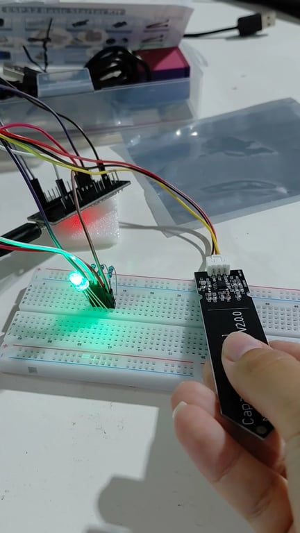 ESP32 breadboard circuit connected to a capacitive soil-moisture sensor and green RGB LED