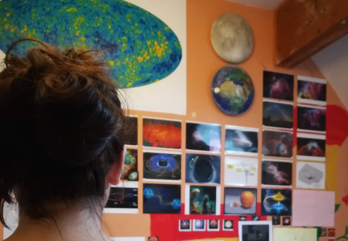Bedroom wall covered in space photos — CMB map, nebulae, planets, black holes