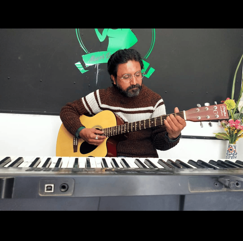 A Music Room instructor playing acoustic guitar in the studio