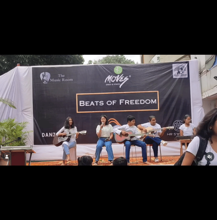 Students performing guitar and vocals at The Music Room's Beats of Freedom event