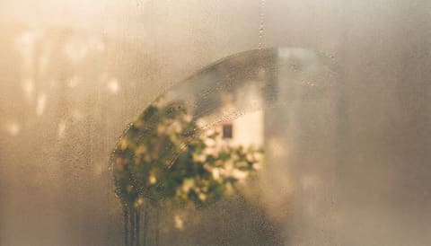 A finger-traced clearing through condensation on a fogged window pane