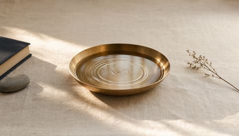 Concentric ripples in still water in a shallow brass dish on cream linen