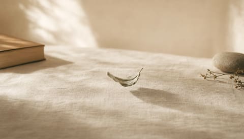 A single leaf appearing unsettled and agitated on cream linen