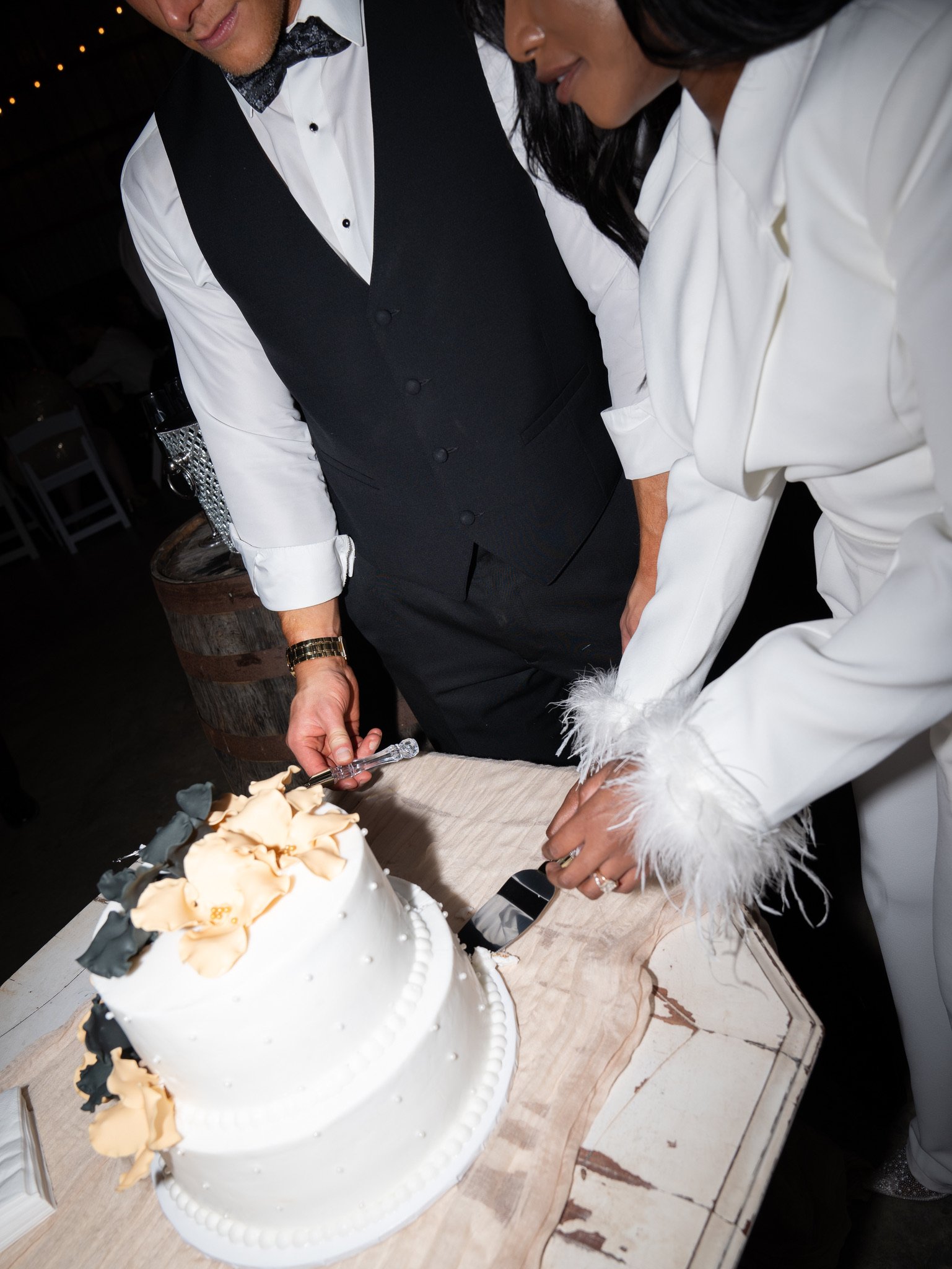 Ashley and Jason cut a white cake decorated with peach flowers together.