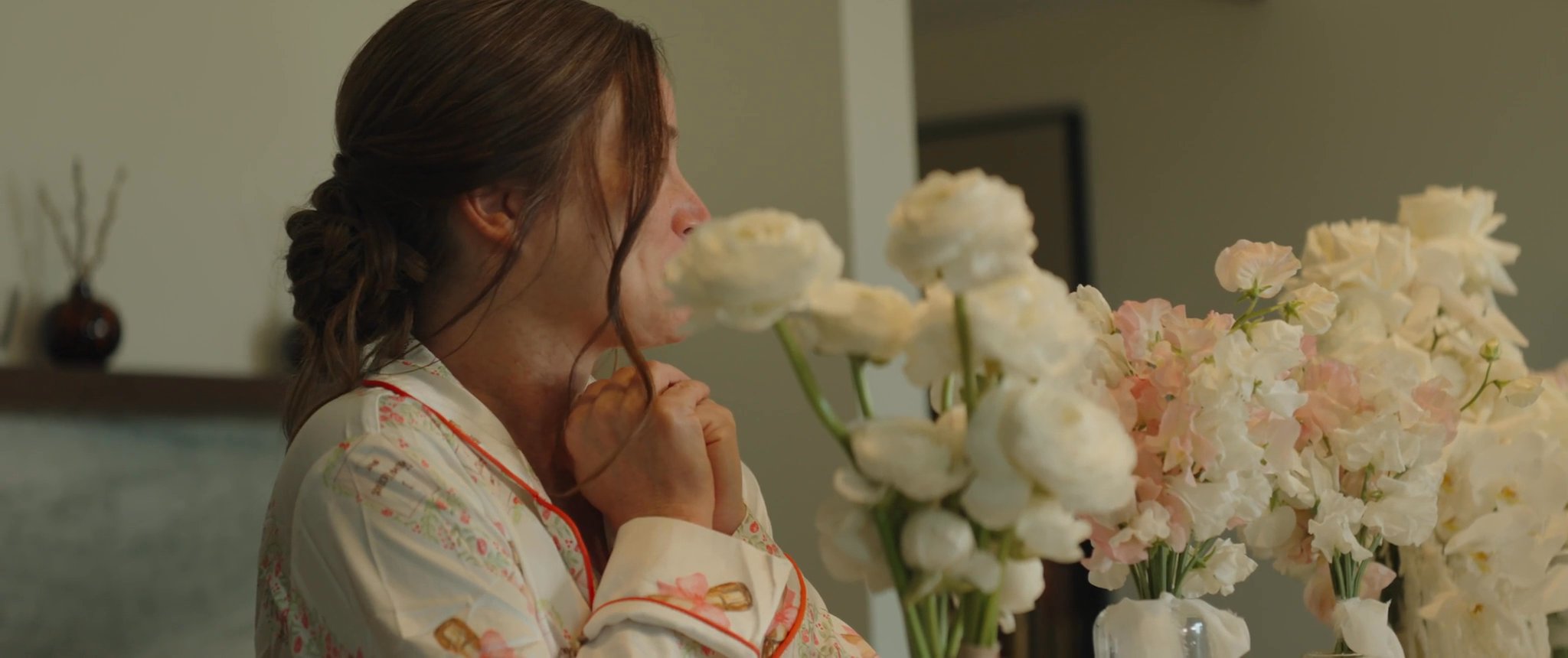 Ally having her makeup finished beside the wedding flowers. Still from their Midsummer Productions wedding film.