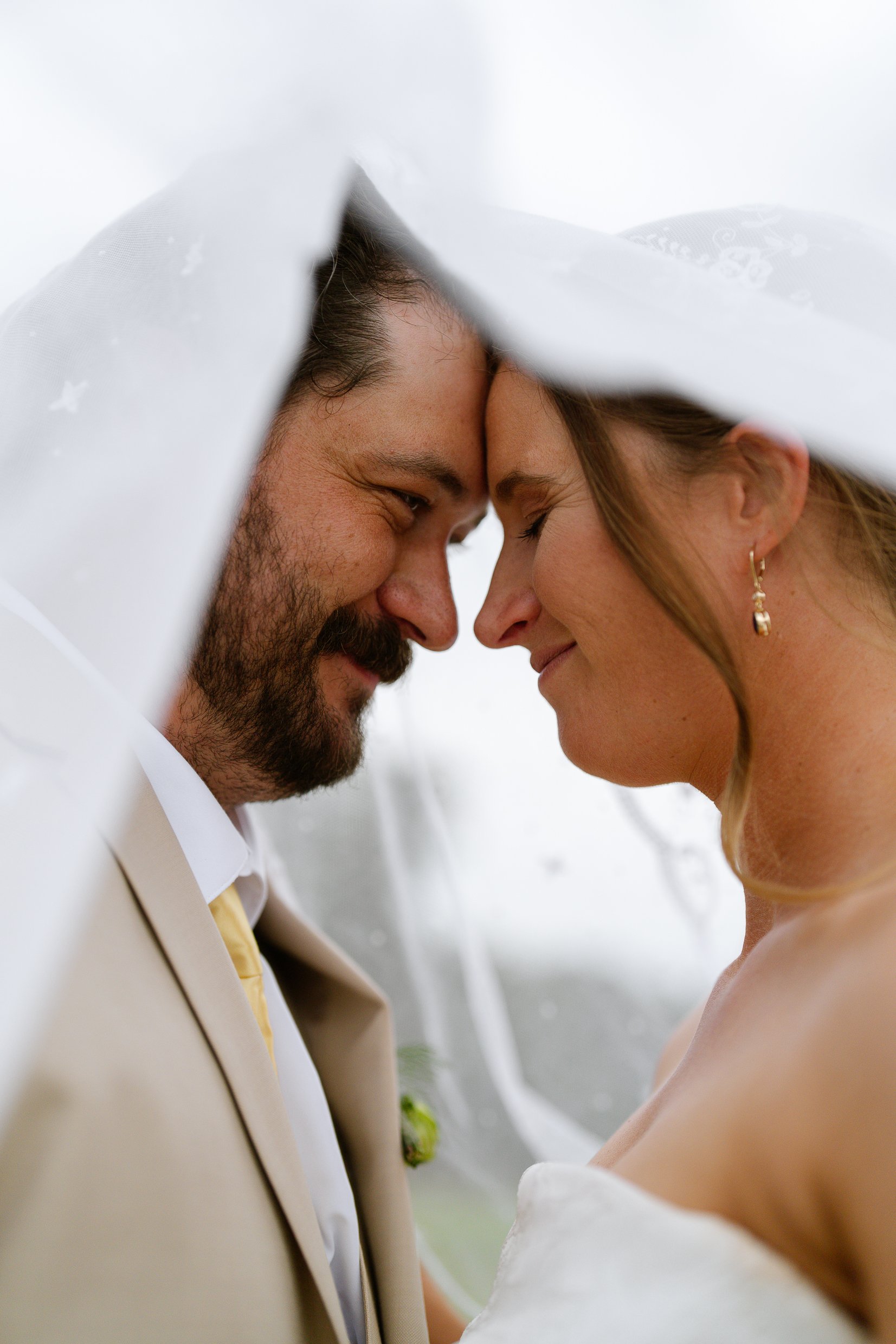Elizabeth and Dustin touch foreheads and smile beneath her veil.