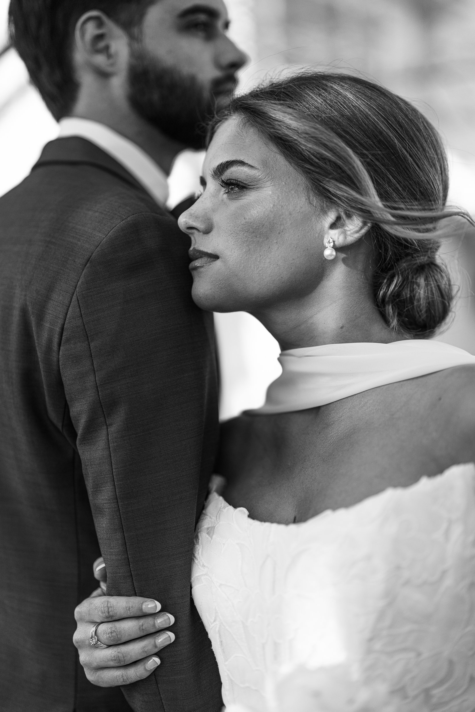 Black and white photo of Joley looking off to the side with her hand on Matthew's arm and his shoulder in the foreground.