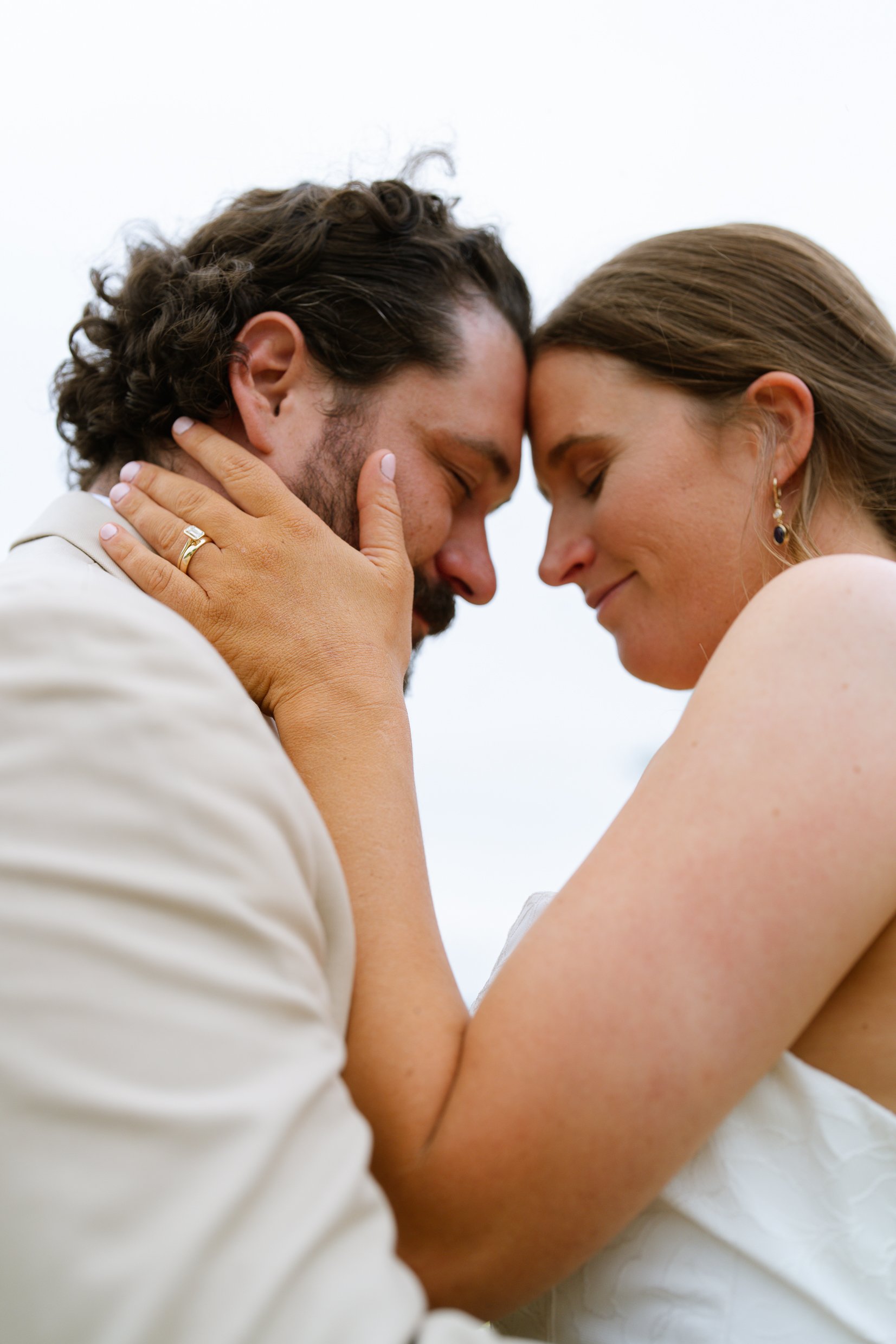 A close view of Elizabeth and Dustin with their foreheads together outdoors, her hand on his cheek.
