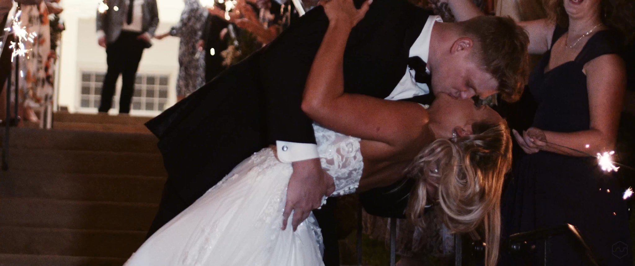 Caleb dips and kisses Madalyn during their sparkler send-off. Still from their Midsummer Productions wedding film.