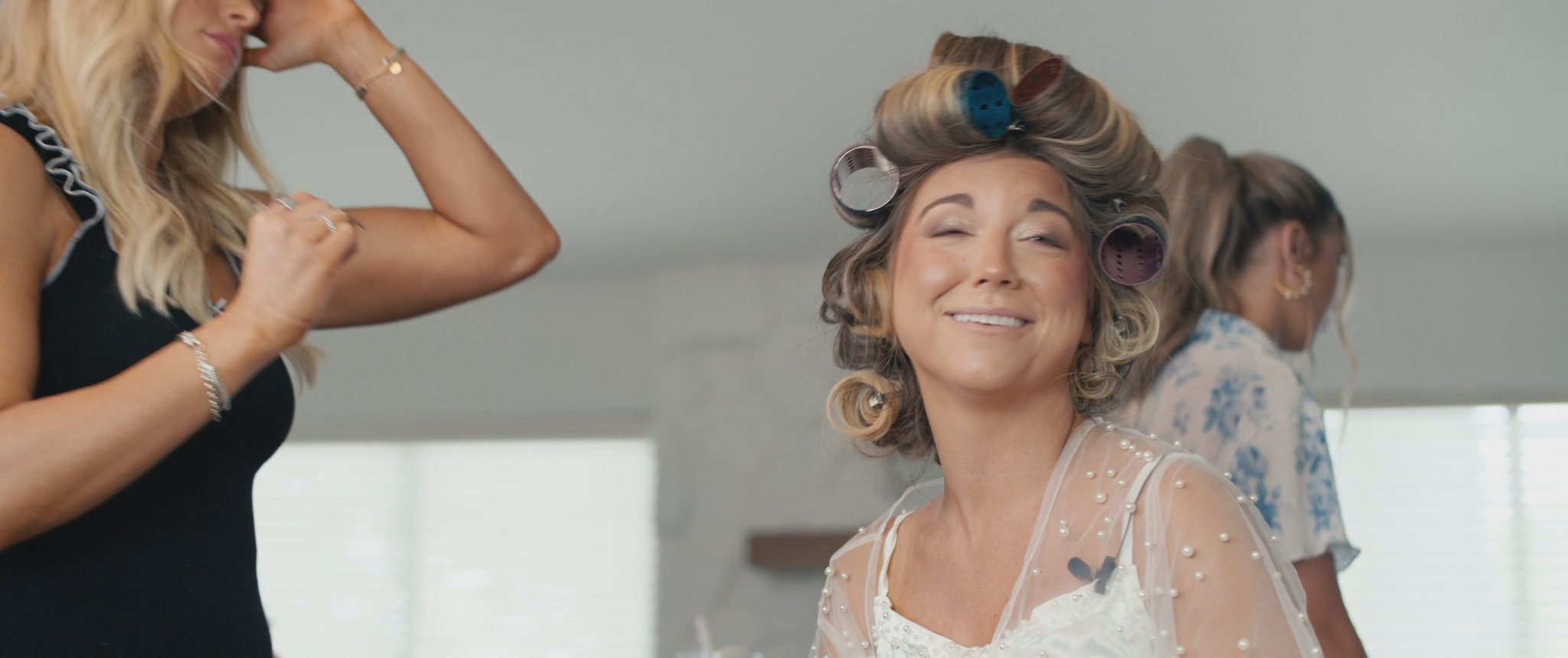 Montana smiling while her hair is being styled. Still from their Midsummer Productions wedding film.
