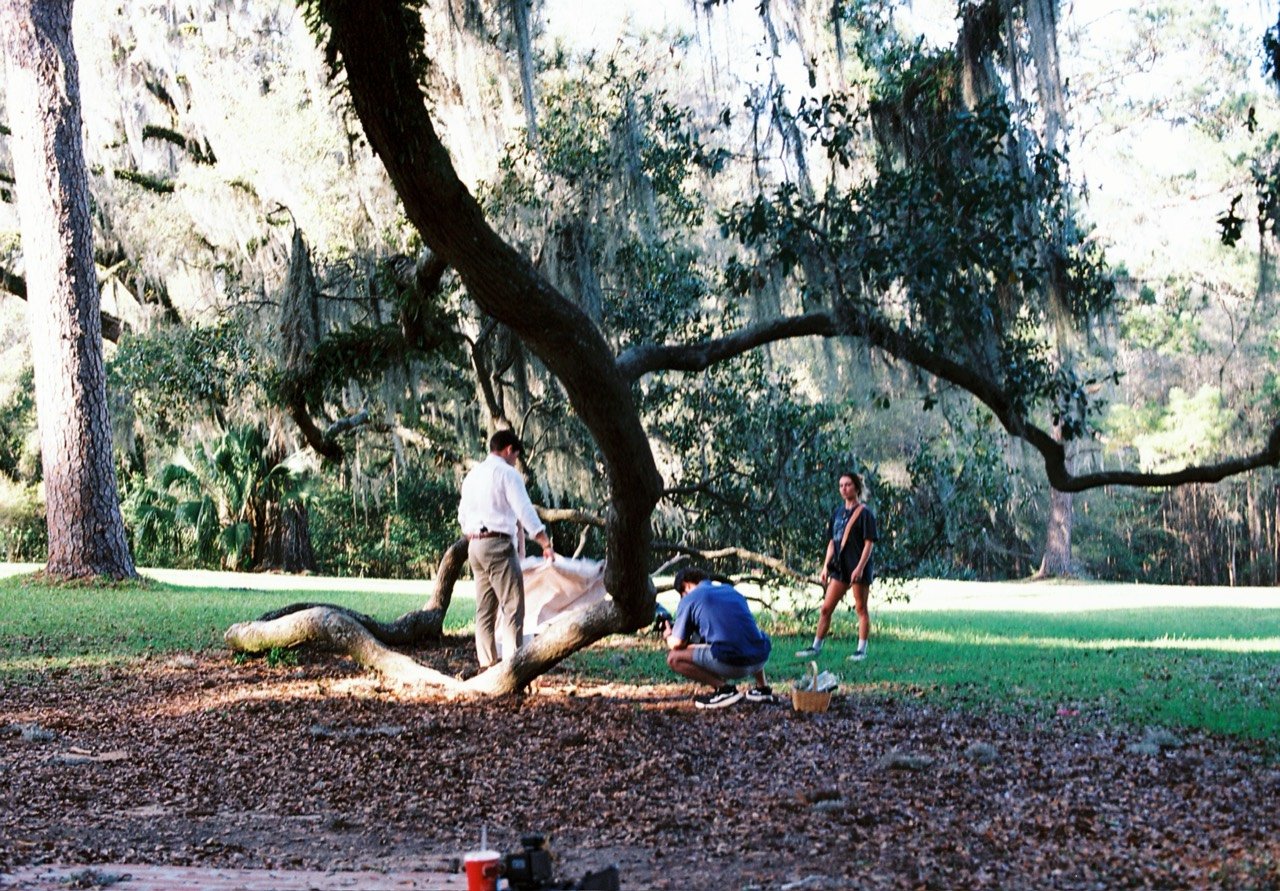 A filmmaker working with a couple beneath a large oak tree at South Eden Plantation, photographed on film.