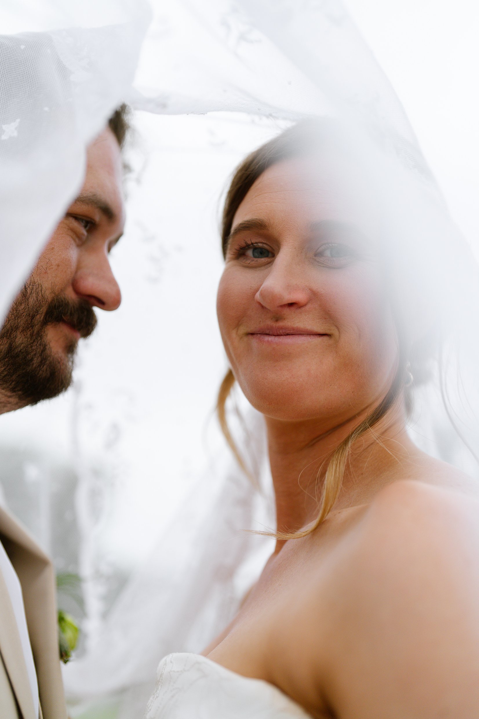 Elizabeth looks at the camera and smiles under her veil while Dustin rests his head against hers.