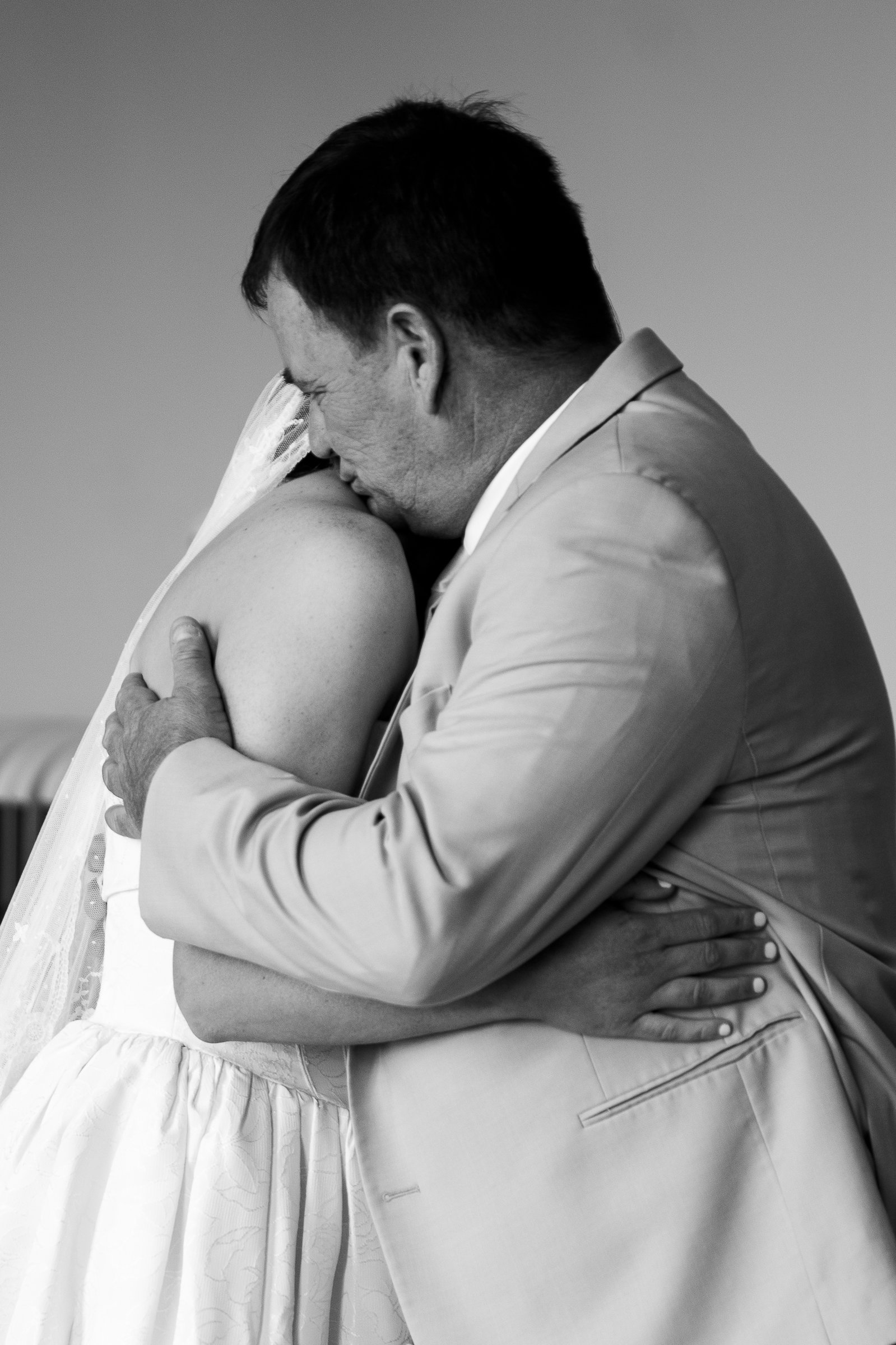In black and white, Elizabeth's father holds her close, his face pressed against her veil.
