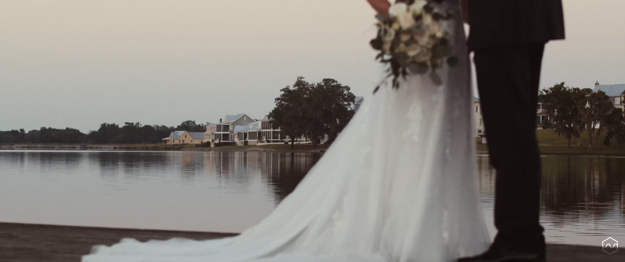Madalyn’s wedding dress and Caleb’s suit beside the water after their ceremony. Still from their Midsummer Productions wedding film.