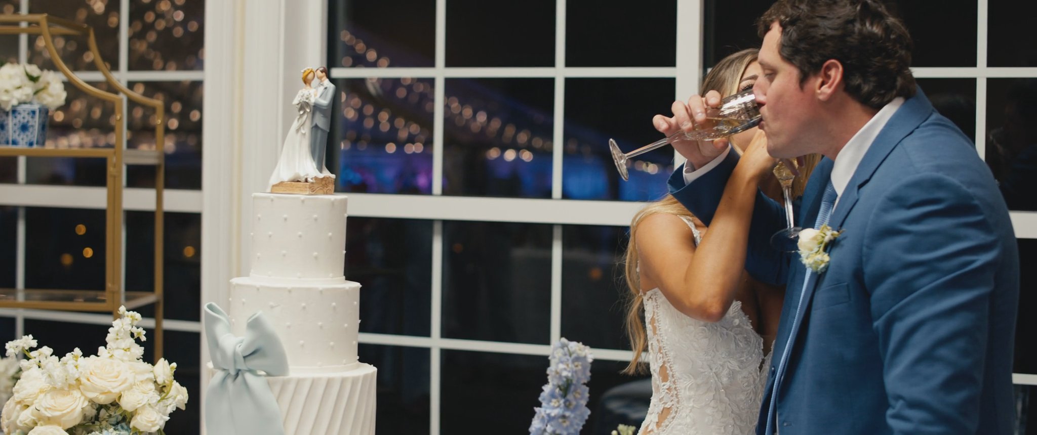 Montana and Cam celebrating beside their wedding cake. Still from their Midsummer Productions wedding film.