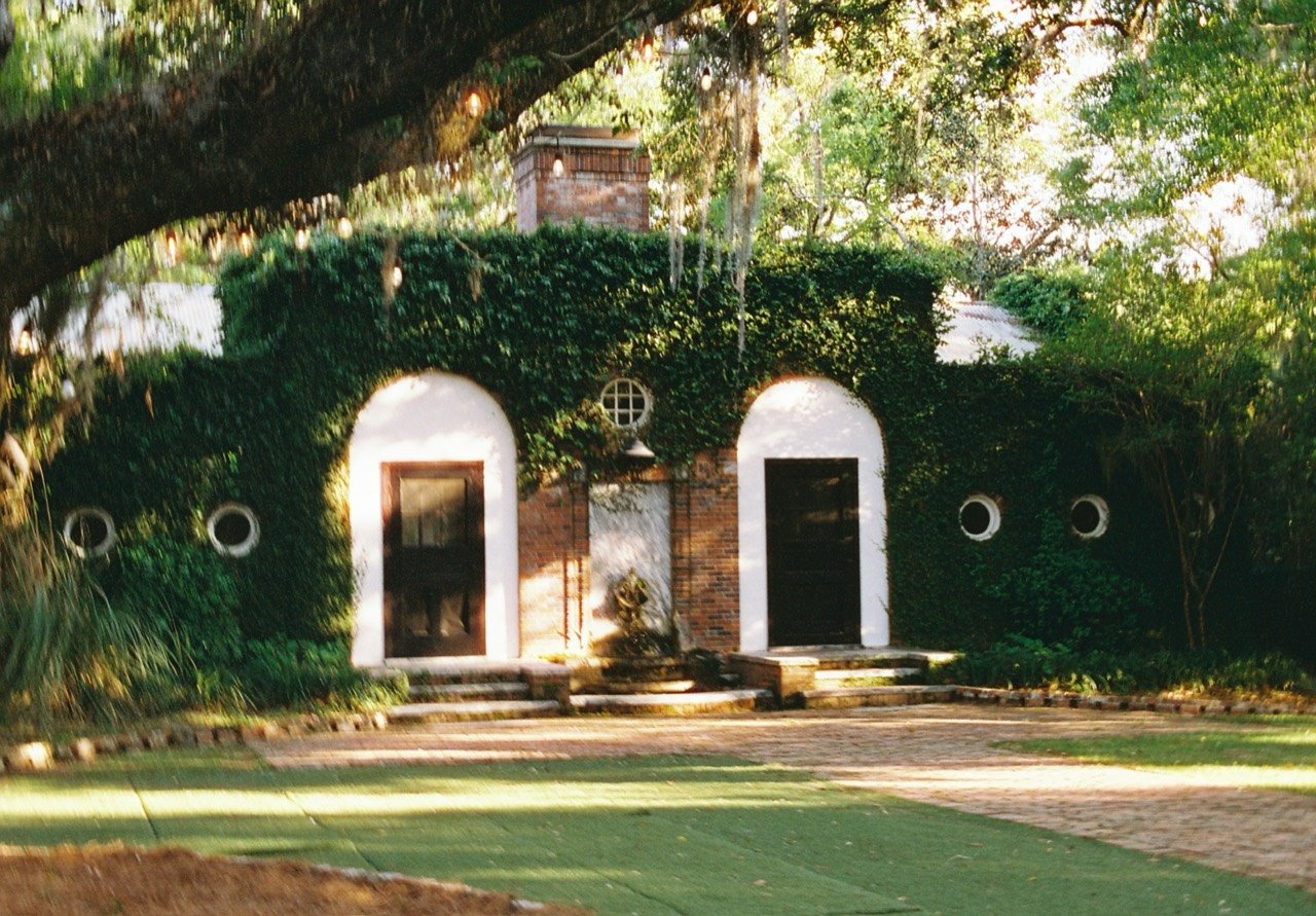 An ivy-covered brick building with arched doorways and a fountain at South Eden Plantation, photographed on film.